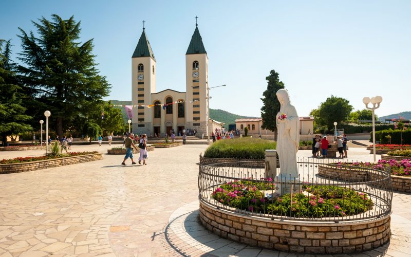 Medjugorje Sanctuary in Bosnia and Herzegovina. In the foreground is the vigin Mary statue and in the background is the parish church.